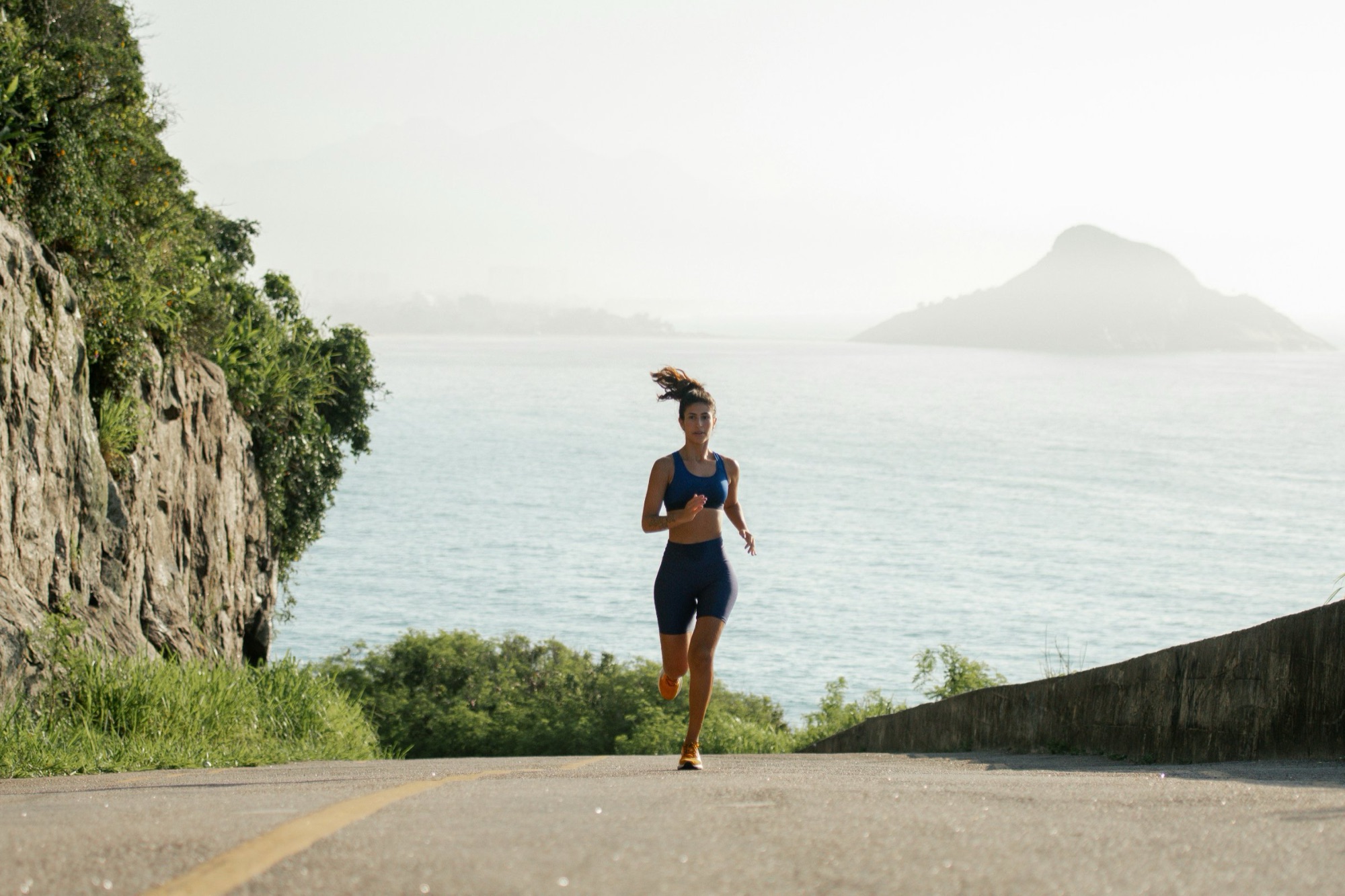 Endurance runner training on a coastal road above the water