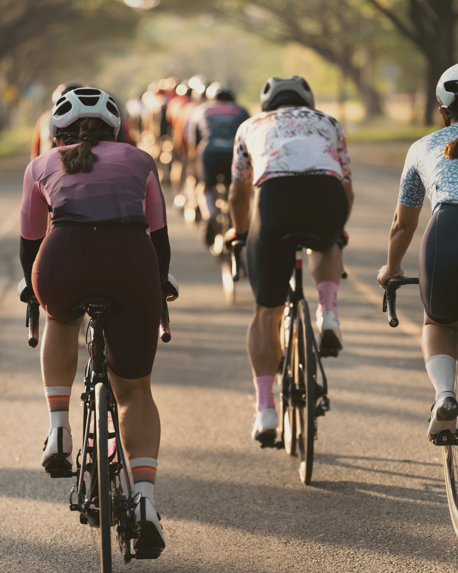 Endurance group ride on a tree-lined road at golden hour — a relaxed, aspirational team approach to RED-S recovery